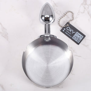 Anal plug with a shiny chrome finish and integrated ashtray-style top, designed for BDSM roleplay and humiliation scenes.