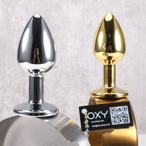 Shiny silver and gold anal plugs with tapered tips, displayed on a metallic surface, emphasizing their smooth, reflective surfaces.